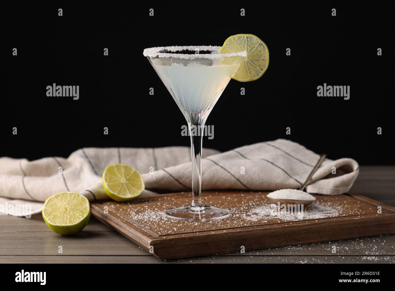 Martini bicchiere di cocktail rinfrescante con lime e zucchero su tavolo di legno su sfondo nero Foto Stock