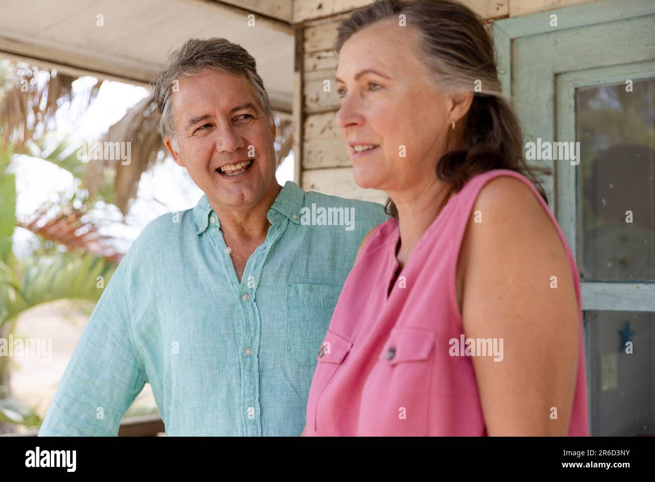 Un uomo anziano caucasico sorridente che guarda una bella moglie mentre si trova in balcone al cottage Foto Stock