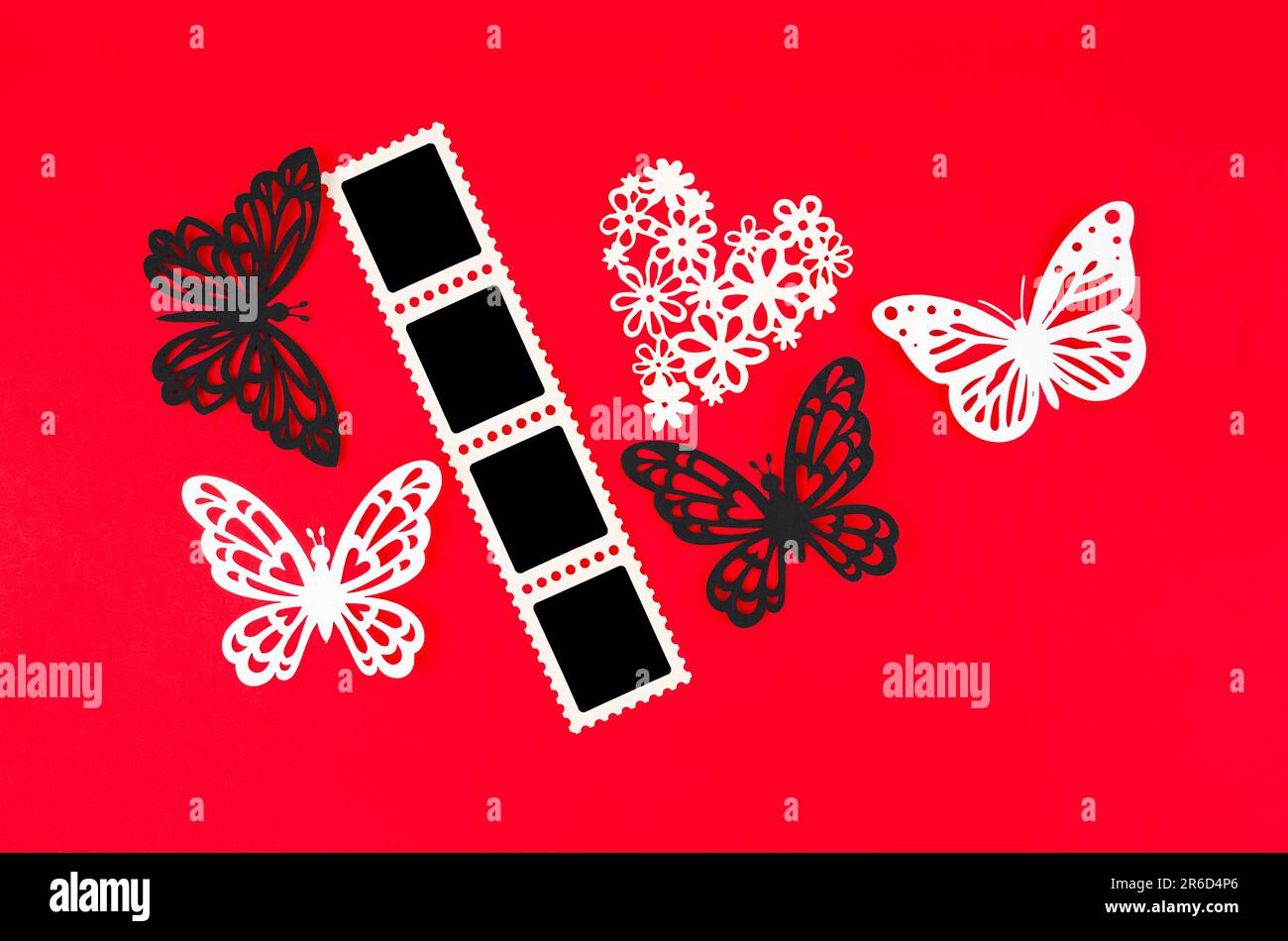 Cornici di carta fotografica a strisce cinematografiche con carta a farfalla su sfondo rosso. Salva tracciato di ritaglio. Foto Stock