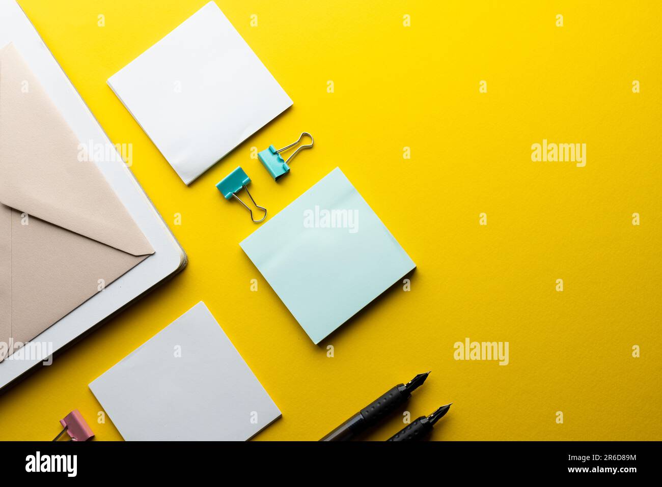 Disposizione piatta di penne, buste, graffette e note nere con spazio per la copia su sfondo giallo. Materiali scolastici, scrittura, colorazione, disegno, porro Foto Stock