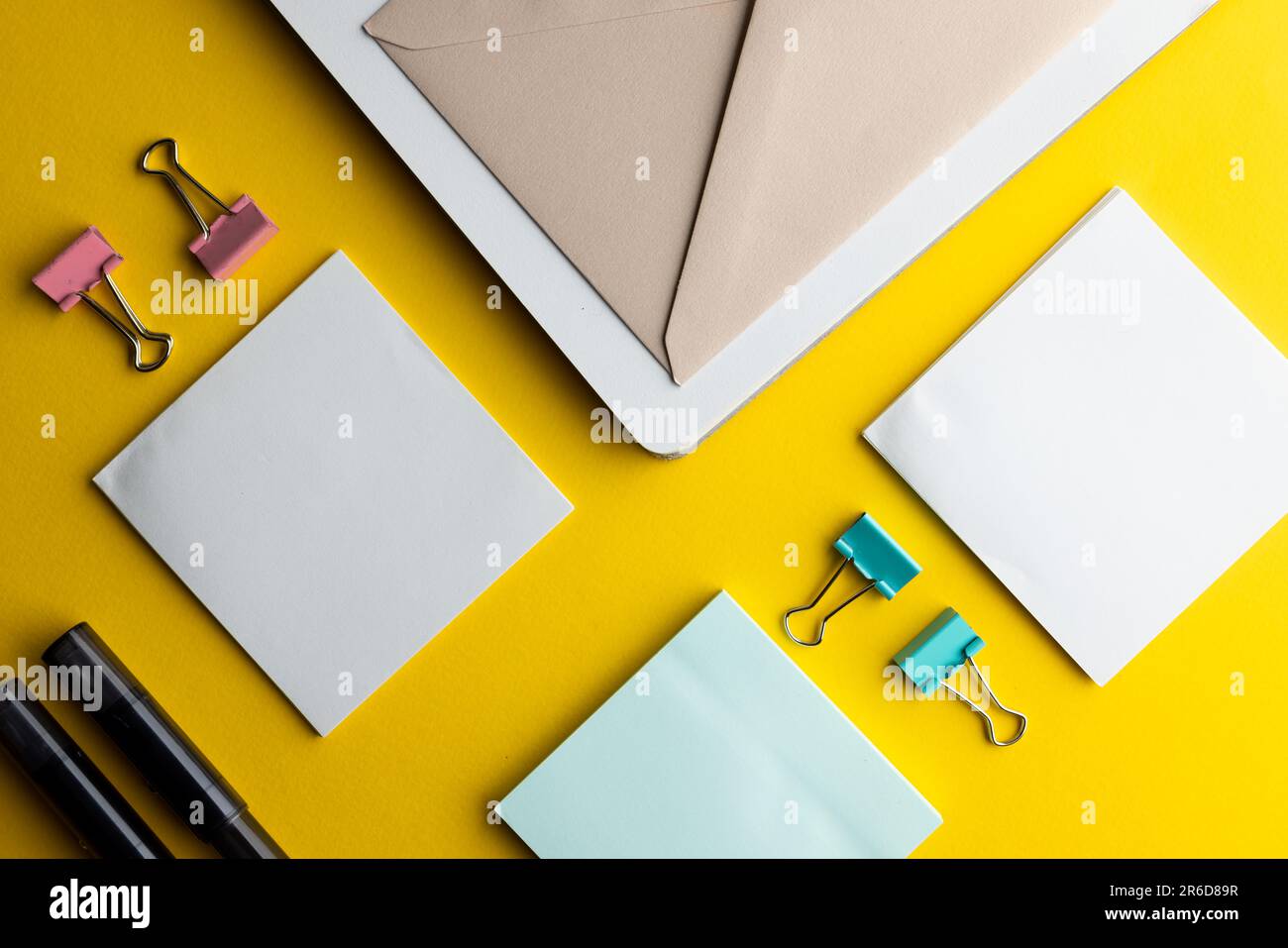 Disposizione piatta di penne nere, buste e carta bianca con spazio per la copia su sfondo giallo. Materiali scolastici, scrittura, colorazione, disegno, apprendimento, scuola Foto Stock