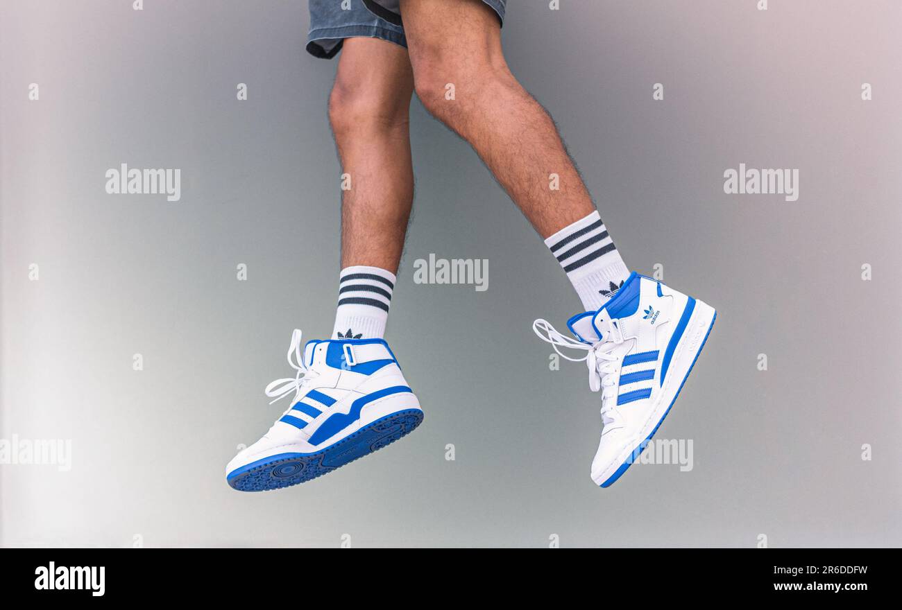 Un giovane uomo salta in su in Adidas Forum sneakers Mid bianco e blu il 20 maggio 2023 a Bangkok, Thailandia. Foto Stock