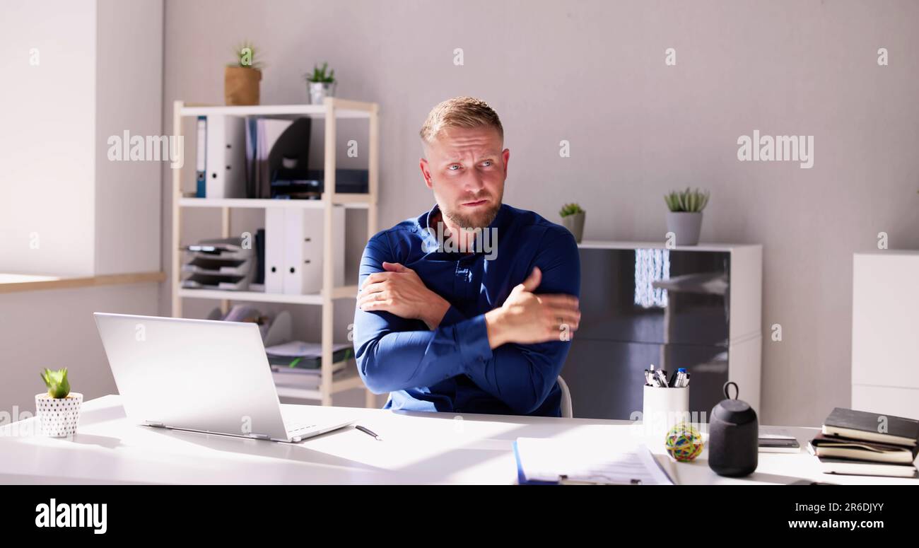 Young Man Feeling the Cold Inside Office Foto Stock