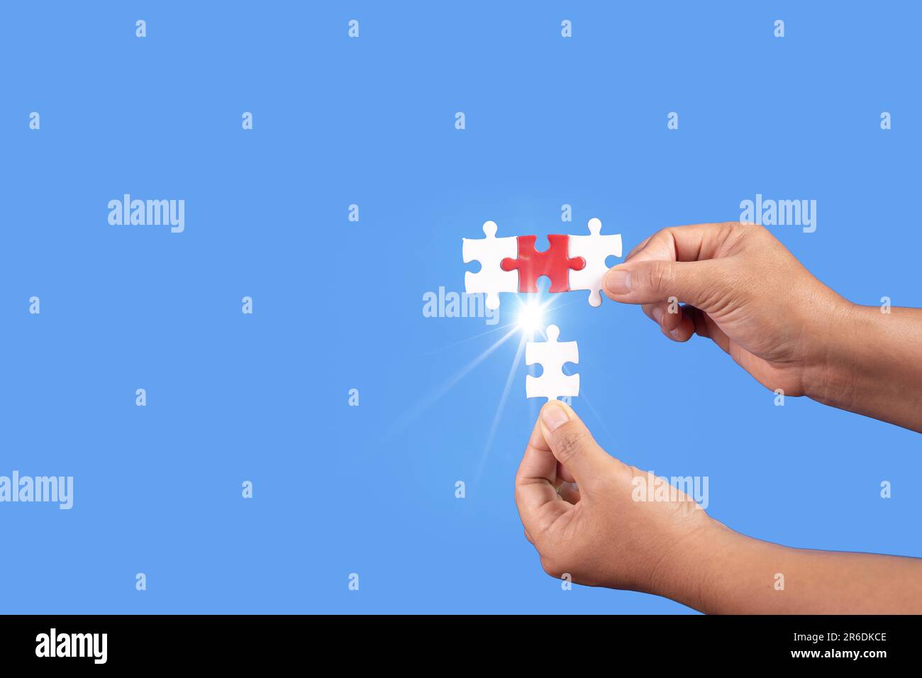 Mani che tengono jigsaw puzzle pezzo con sfondo blu chiaro, business di successo, strategia di soluzione, concetto di partnership lavoro di squadra Foto Stock