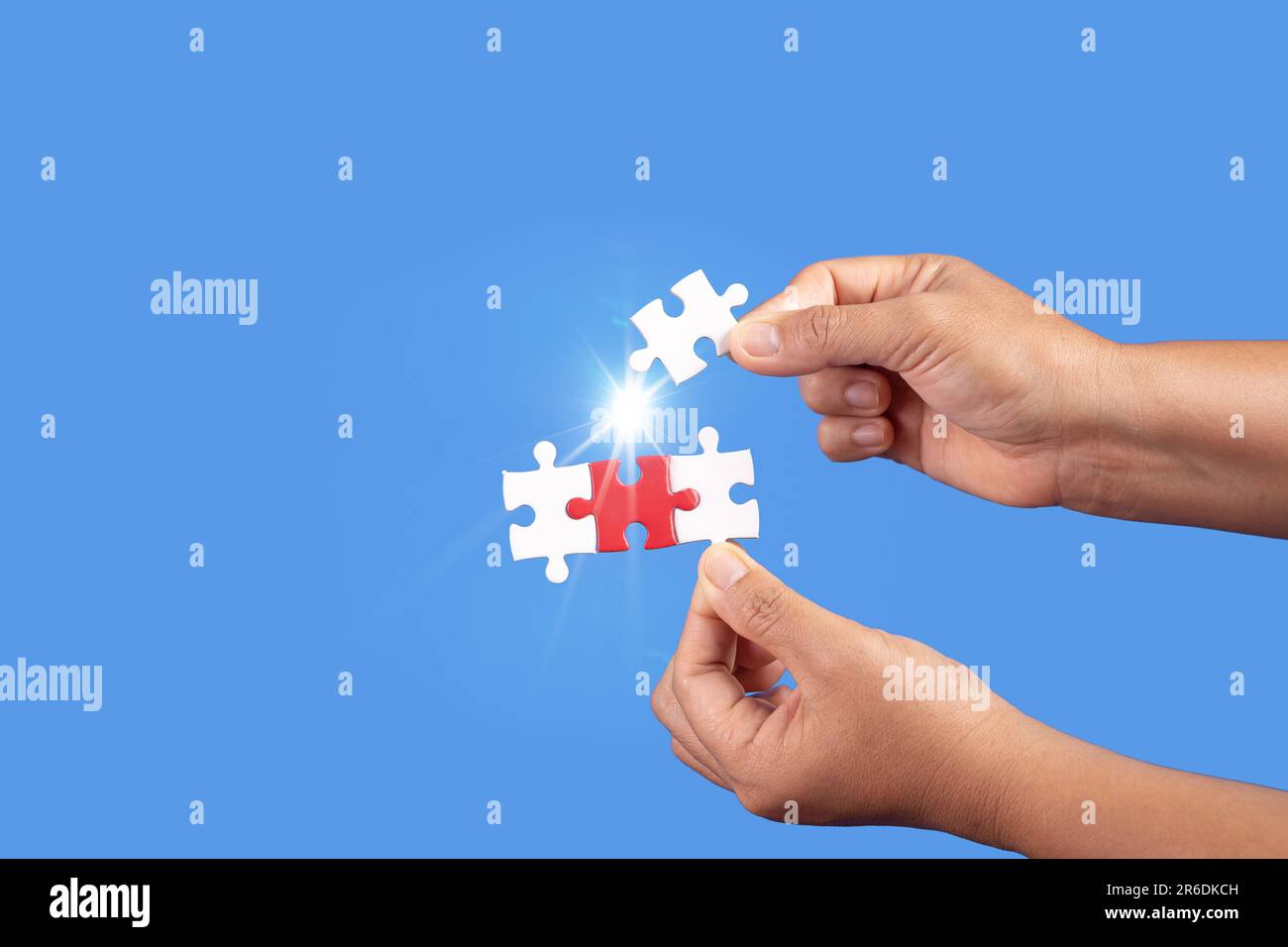 Mani che tengono jigsaw puzzle pezzo con sfondo blu chiaro, business di successo, strategia di soluzione, concetto di partnership lavoro di squadra Foto Stock