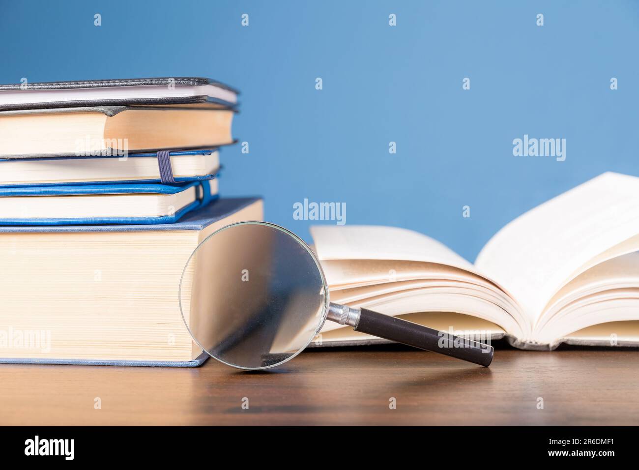 Pila libro con lente d'ingrandimento su scrivania di legno in biblioteca di informazioni della scuola o dell'università, concetto per l'istruzione, la lettura, lo studio, copia spazio su b Foto Stock
