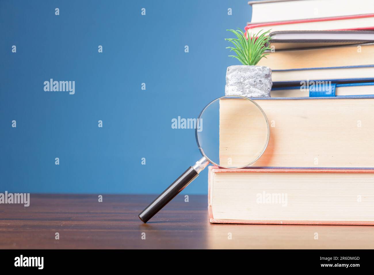 Pila libro con lente d'ingrandimento su scrivania di legno in biblioteca di informazioni della scuola o dell'università, concetto per l'istruzione, la lettura, lo studio, copia spazio su b Foto Stock