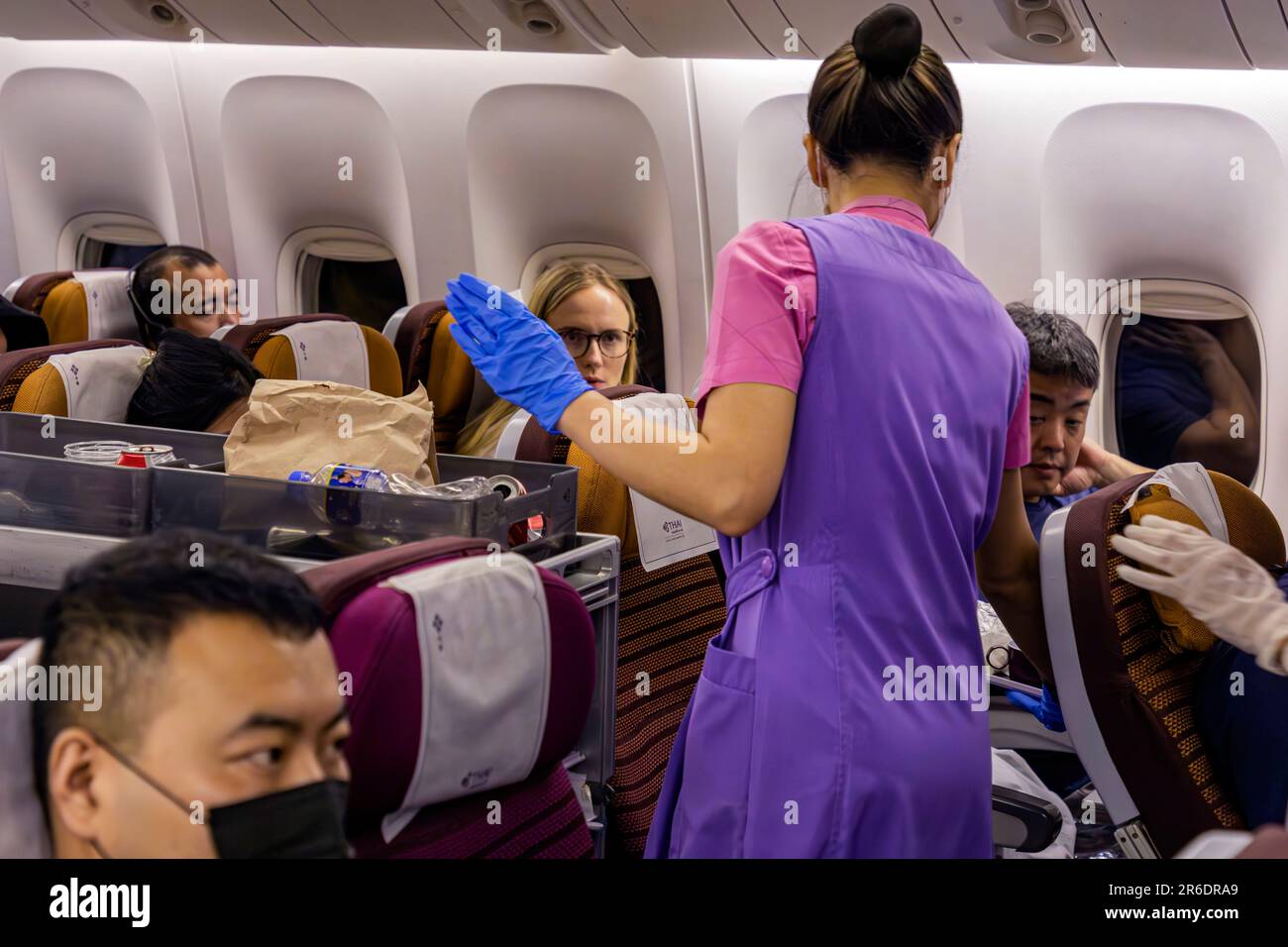 L'equipaggio di cabina della Thai Airways indossa un facemask che serve i passeggeri nella sezione Economy sul volo internazionale da Manila a Bangkok Foto Stock