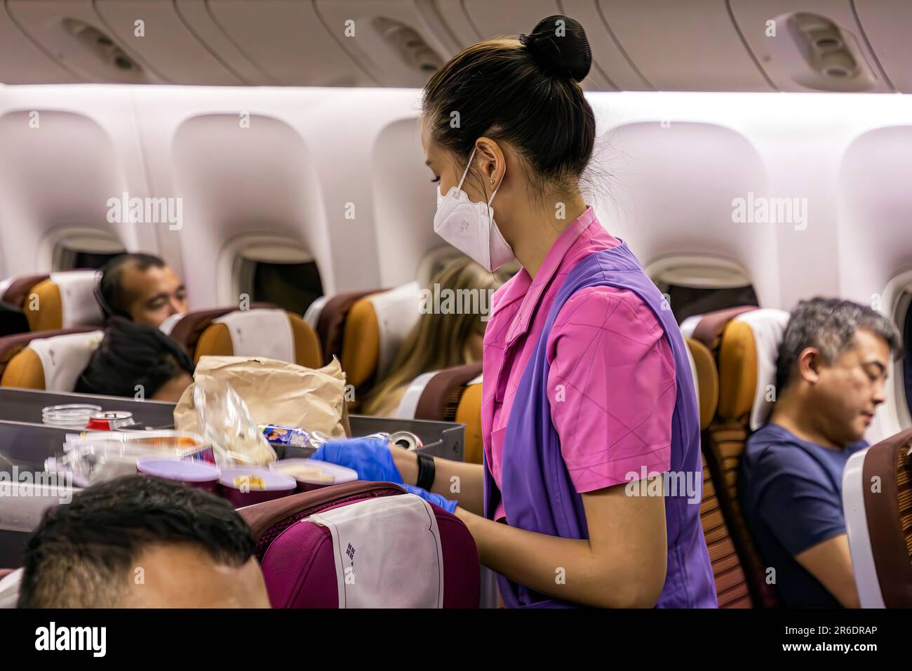 L'equipaggio di cabina della Thai Airways indossa un facemask che serve i passeggeri nella sezione Economy sul volo internazionale da Manila a Bangkok Foto Stock