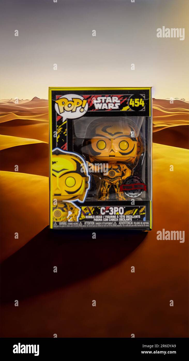 Un'immagine di una figura pop di Star Wars C-3PO circondata da sabbia desertica in un paesaggio vibrante Foto Stock