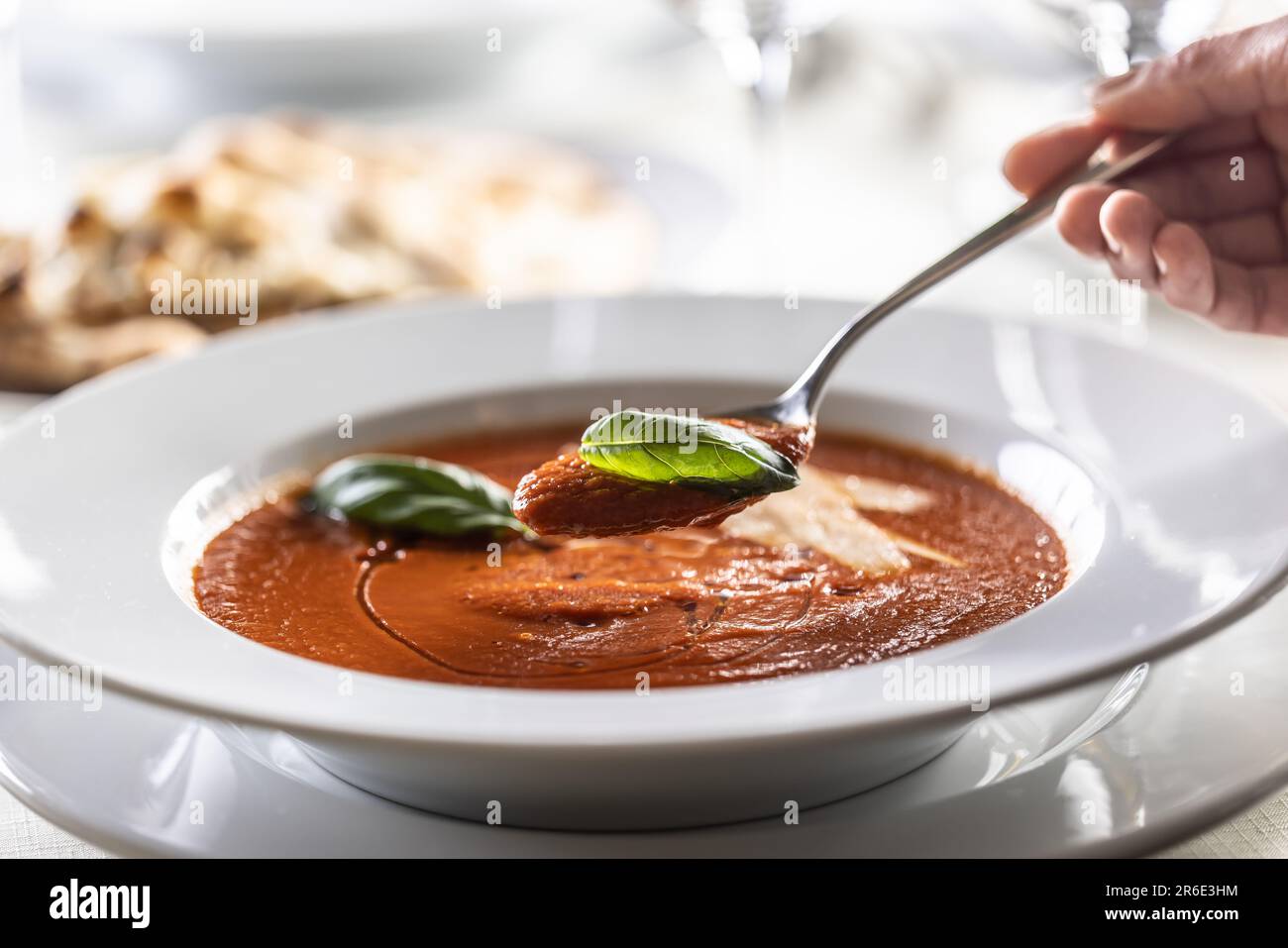 Zuppa di pomodoro italiana densa e cremosa con basilico mangiato da un piatto con un cucchiaio. Foto Stock