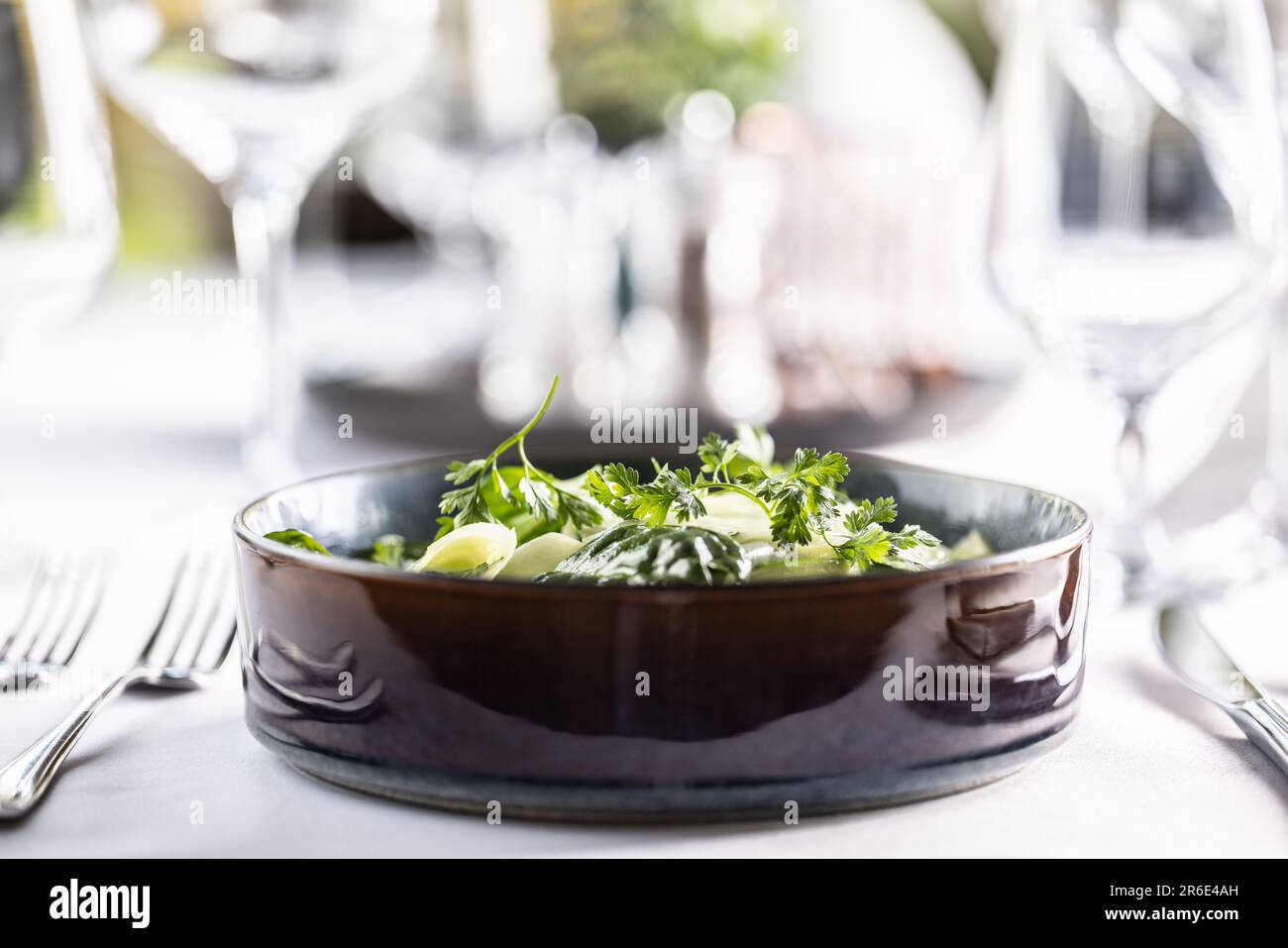 Foto laterale di una ciotola scura riempita con kohlrabi e insalata verde di spinaci. Foto Stock