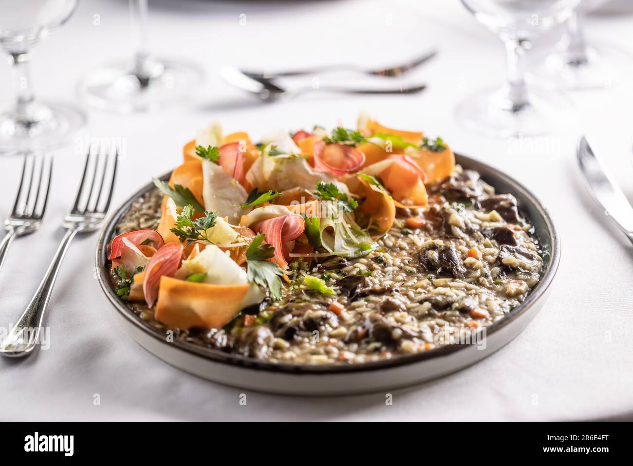 Piatto pieno di cremoso risotto di funghi di riso aroborio con strisce di verdure di radice. Foto Stock
