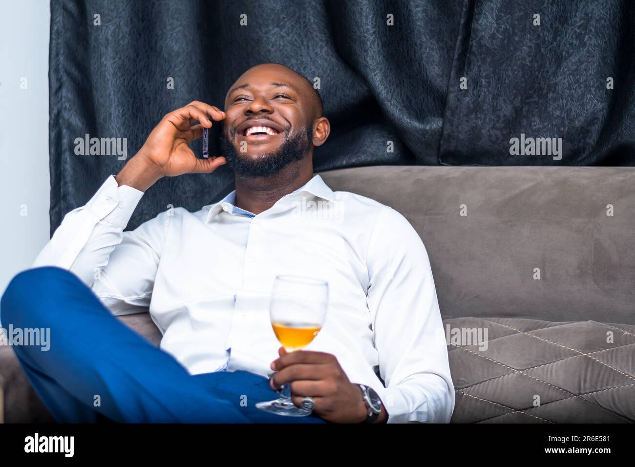giovane eccitato che comunica con il telefono cellulare in possesso di un wineglass Foto Stock