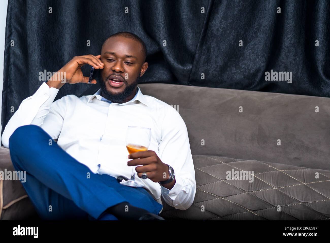 giovane eccitato che comunica con il telefono cellulare in possesso di un wineglass Foto Stock