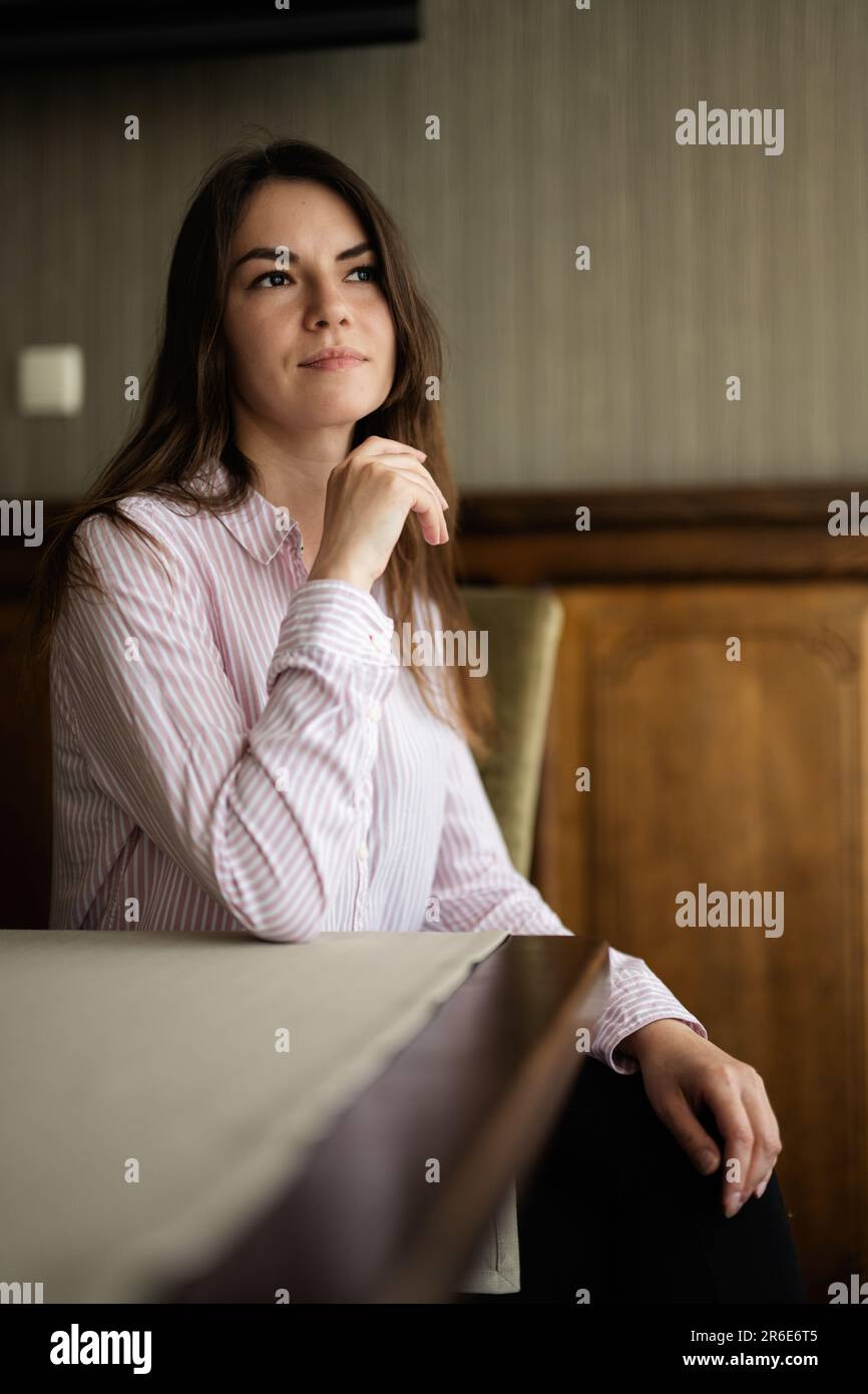 Giovane bella donna brunette sedersi al bar caffetteria ristorante interno. Foto Stock