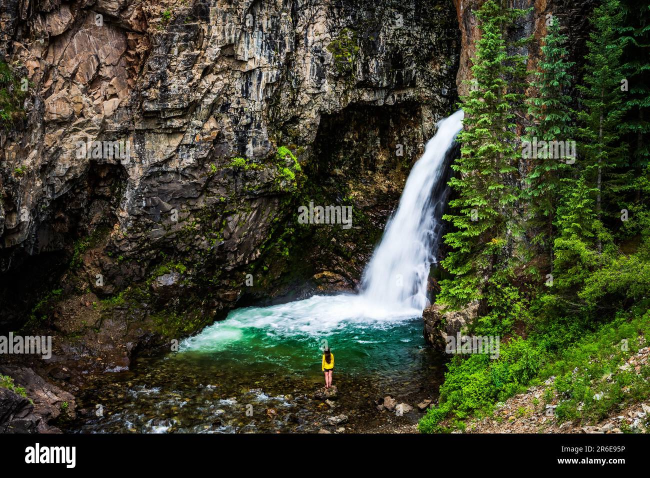 Donna in giallo ad una cascata lungo la strada Alpine Loop Byway Foto Stock