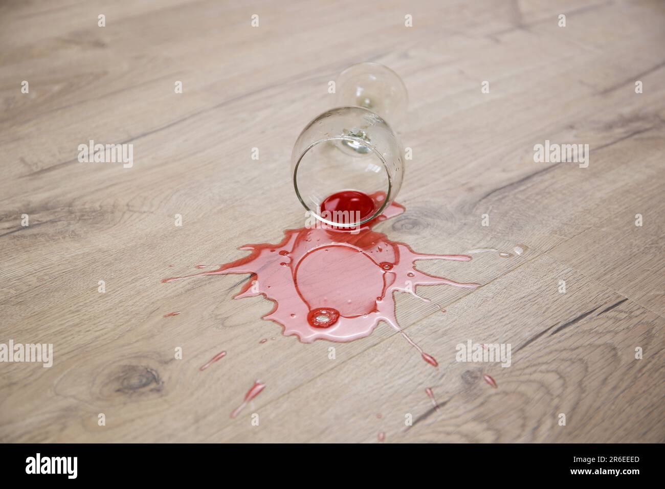 Un bicchiere di vino rosso cadde sul laminato, il vino versato sul pavimento. Foto Stock