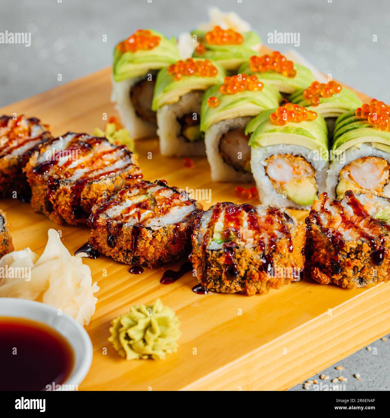 Un piatto con un assortimento di colorati sushi giapponesi, sormontato da oche di pesce, semi di sesamo e cipolla verde Foto Stock