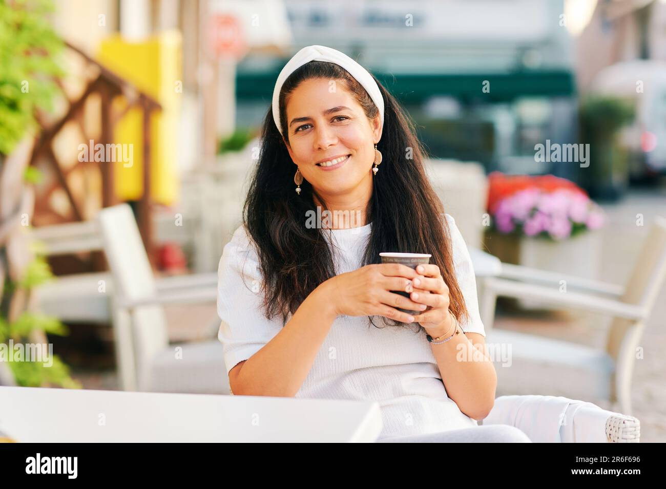 Bellissima donna ispanica di mezza età che beve caffè al mattino sulla terrazza del caffè Foto Stock