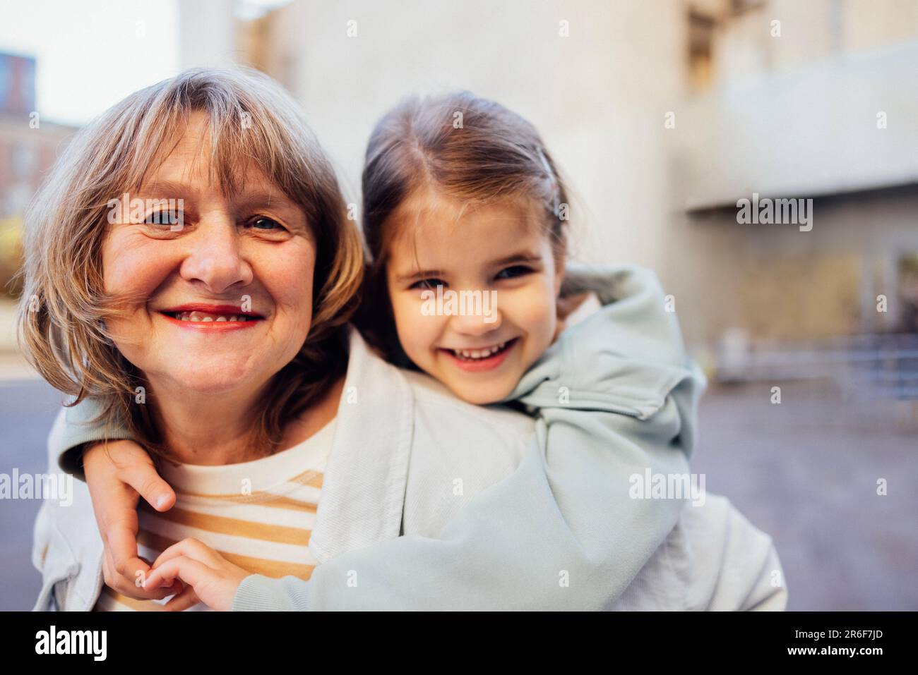 Bambina che abbraccia una donna di mezza età sorridente. La ragazza carina e sua nonna amano camminare all'aperto. Granny e sua nipote che hanno grande t Foto Stock