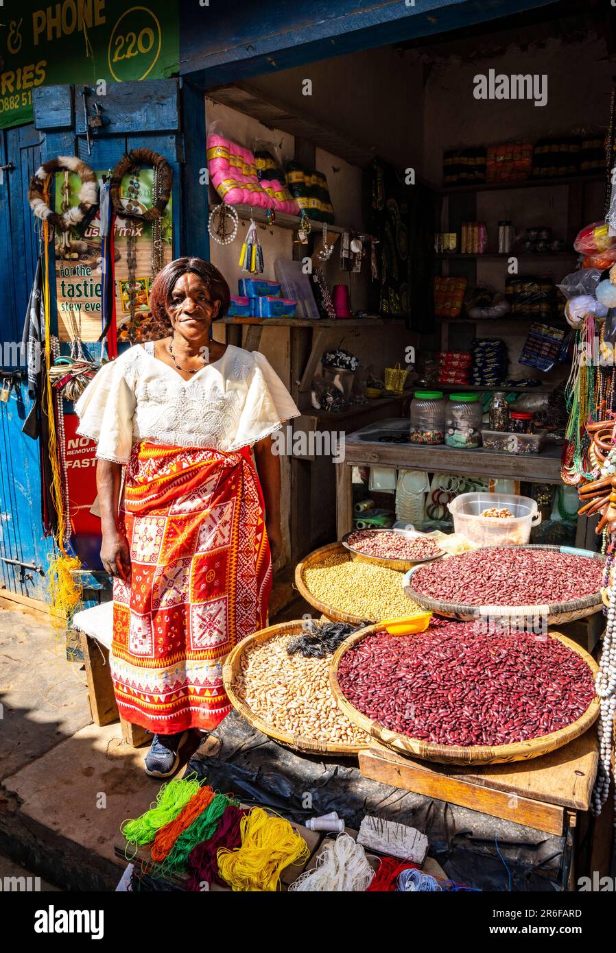 Una donna si trova di fronte al suo negozio di mercato a Mzuzu, Malawi Foto Stock