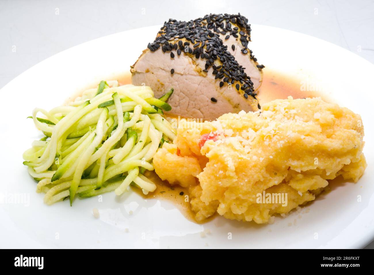 Filetto di maiale laccato mignon con semi di sesamo e polenta con pomodoro. Operazione 'Restau college' sul mangiare bene nelle scuole secondarie nel Tarn-et-Garonne, oggi alla scuola secondaria Jean-Honore Fragonard, con lo chef Raphael Campas dal ristorante NOUS, Specialites Sud-Ouest a Montauban. Sul menu gamba di pollo con paprika. Filetto di maiale laccato mignon con semi di sesamo e polenta con pomodoro. Tome di ramier, yogurt. Fragole locali con menta o panna montata. Francia, Negrepelisse il 8 giugno 2023. Foto di Patricia Huchot-Boissier/ABACAPRESS.COM Foto Stock