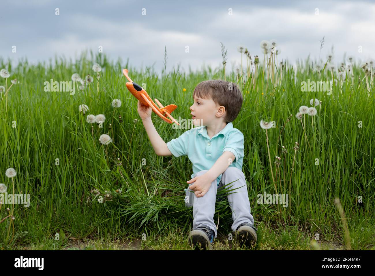 un bambino sogna di diventare un pilota e gioca con un aereo arancione Foto Stock