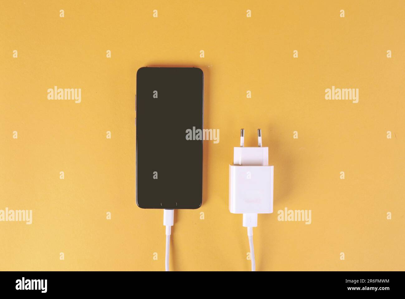 Un telefono cellulare collegato a una presa elettrica e cablato con un cavo di ricarica Foto Stock