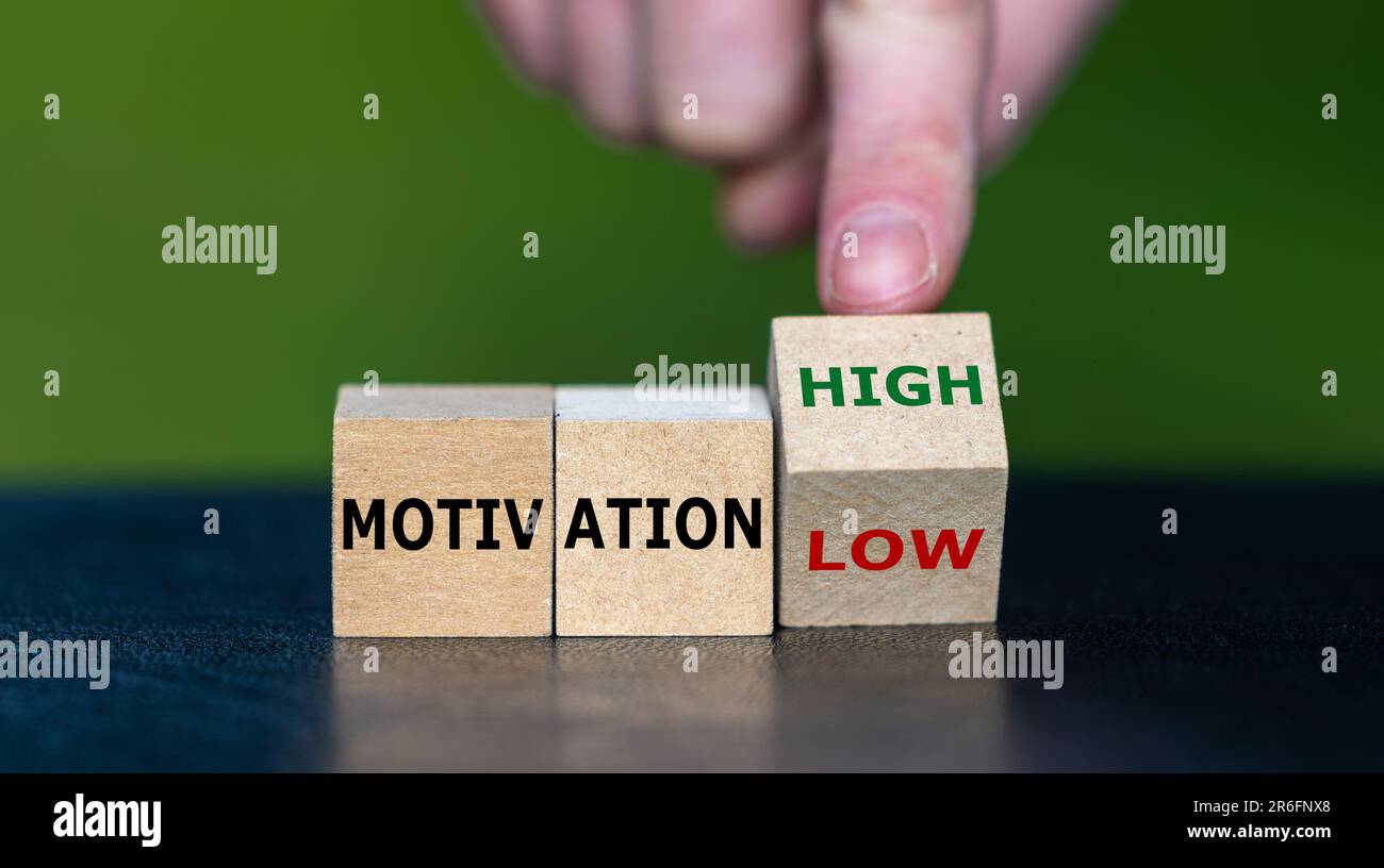 La mano trasforma il cubo di legno e cambia l'espressione "motivation low" in "motivation high". Foto Stock