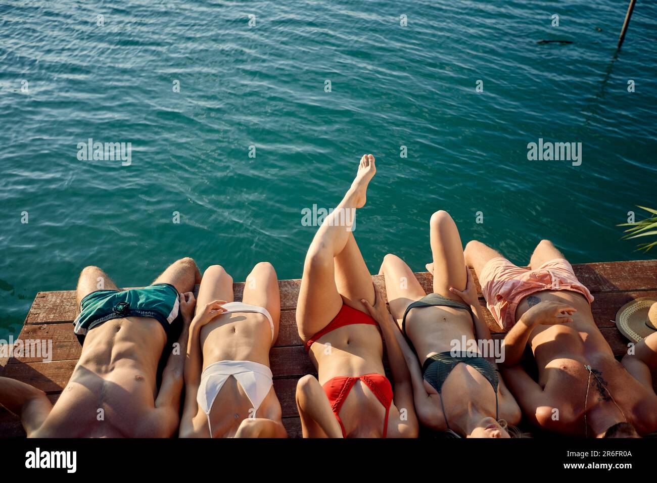 Gruppo di amici che prendono il sole il giorno d'estate insieme sul fiume Foto Stock