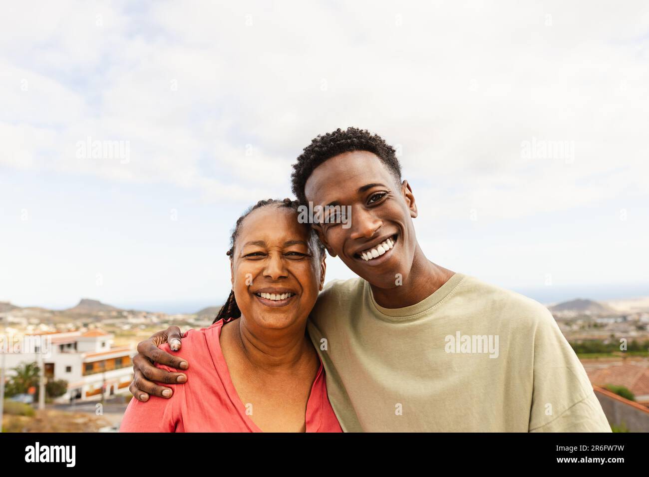 Buon nipote africano che abbraccia sua nonna sul tetto della casa Foto Stock
