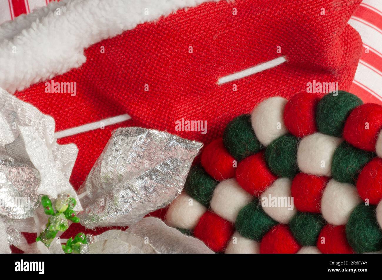 Il tessuto di Natale con spazio di testo sul rosso mostra un bordo forte con feltro, poinsettia e strisce in rosso, bianco, argento e verde. Foto Stock
