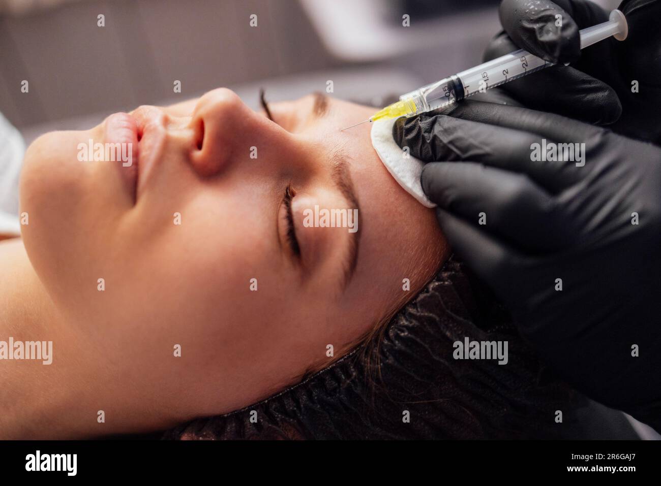 Iniezioni di bellezza. La cosmetologa femminile in guanti trasparenti fa un'iniezione nella mandibola inferiore del suo cliente. Trattamento con acido ialuronico. Introduzione Foto Stock