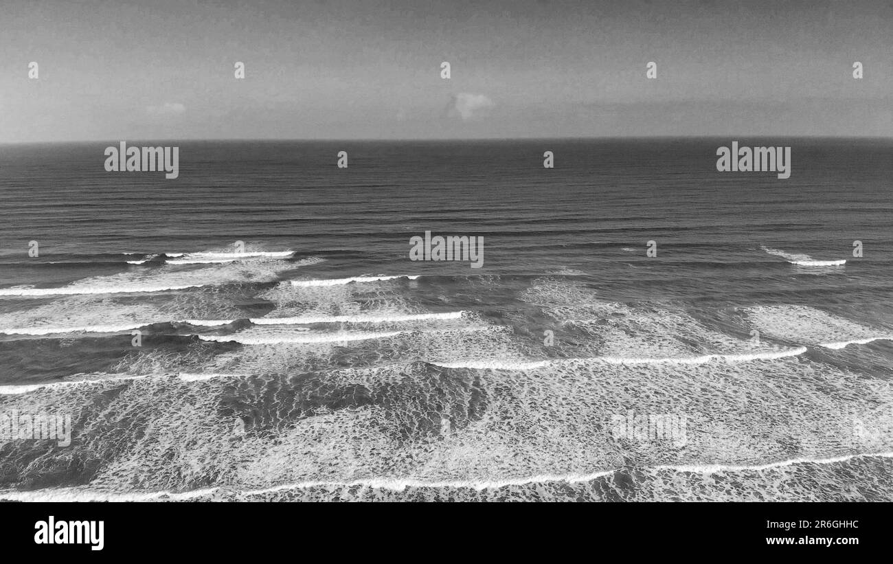 Una spiaggia di sabbia con onde ondulate in una giornata di sole in scala di grigi Foto Stock
