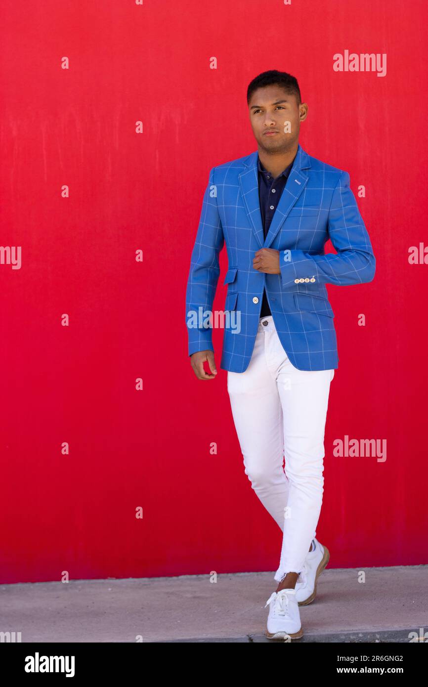 Un giovane uomo adulto che indossa una giacca blu, pantaloni bianchi e  scarpe nere sorride mentre si trova in una strada cittadina Foto stock -  Alamy