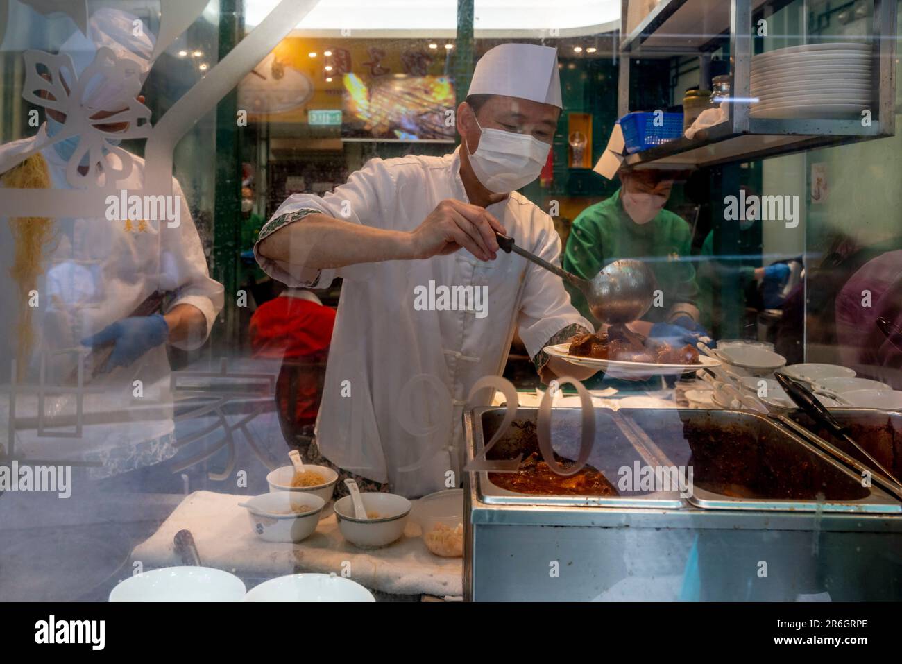 Guardando attraverso Una finestra del ristorante A s Uno Chef serve cibo su Un piatto, Hong Kong, Cina. Foto Stock