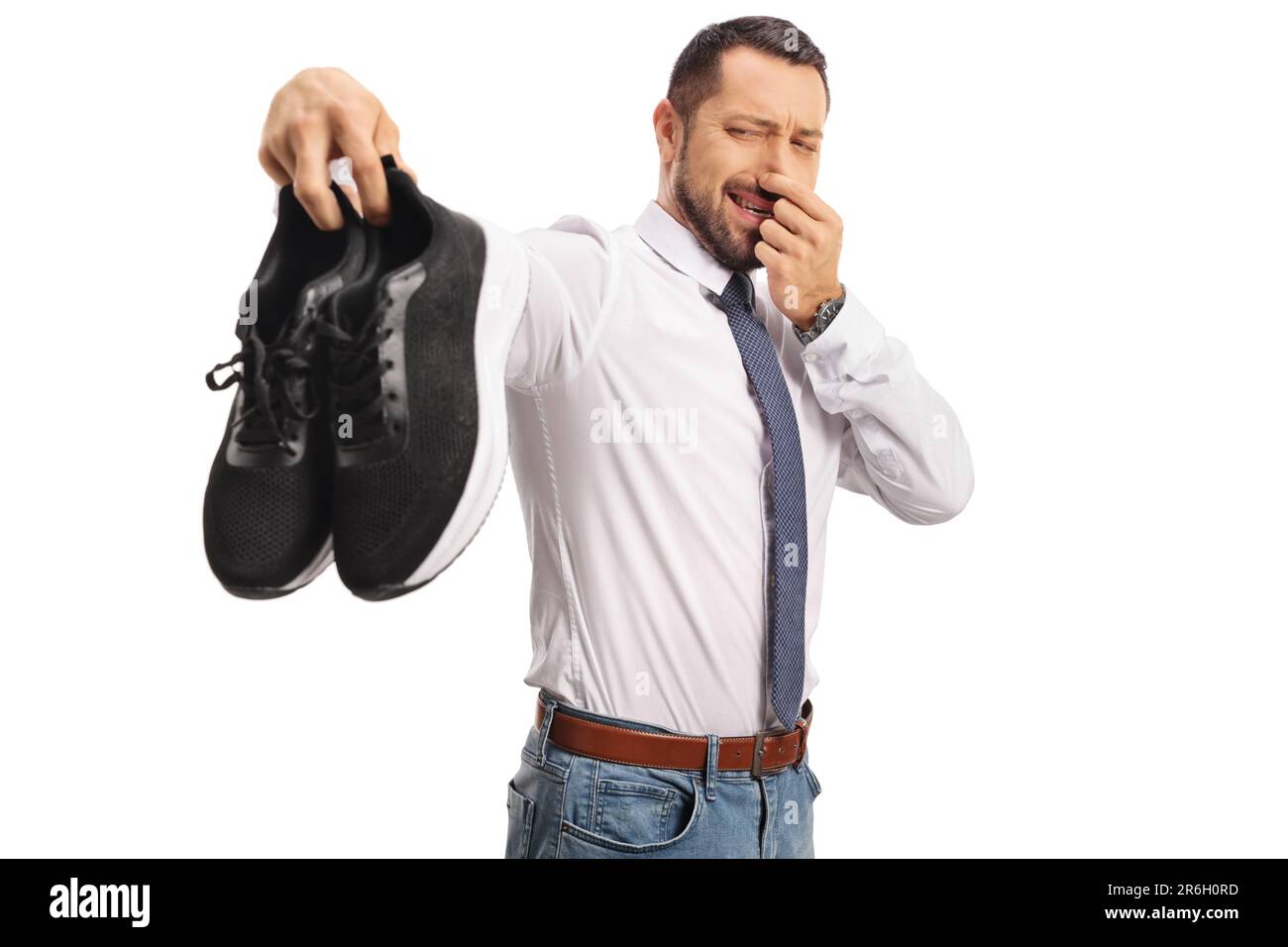 Uomo che tiene un paio di scarpe da ginnastica stinky isolato su sfondo bianco Foto Stock