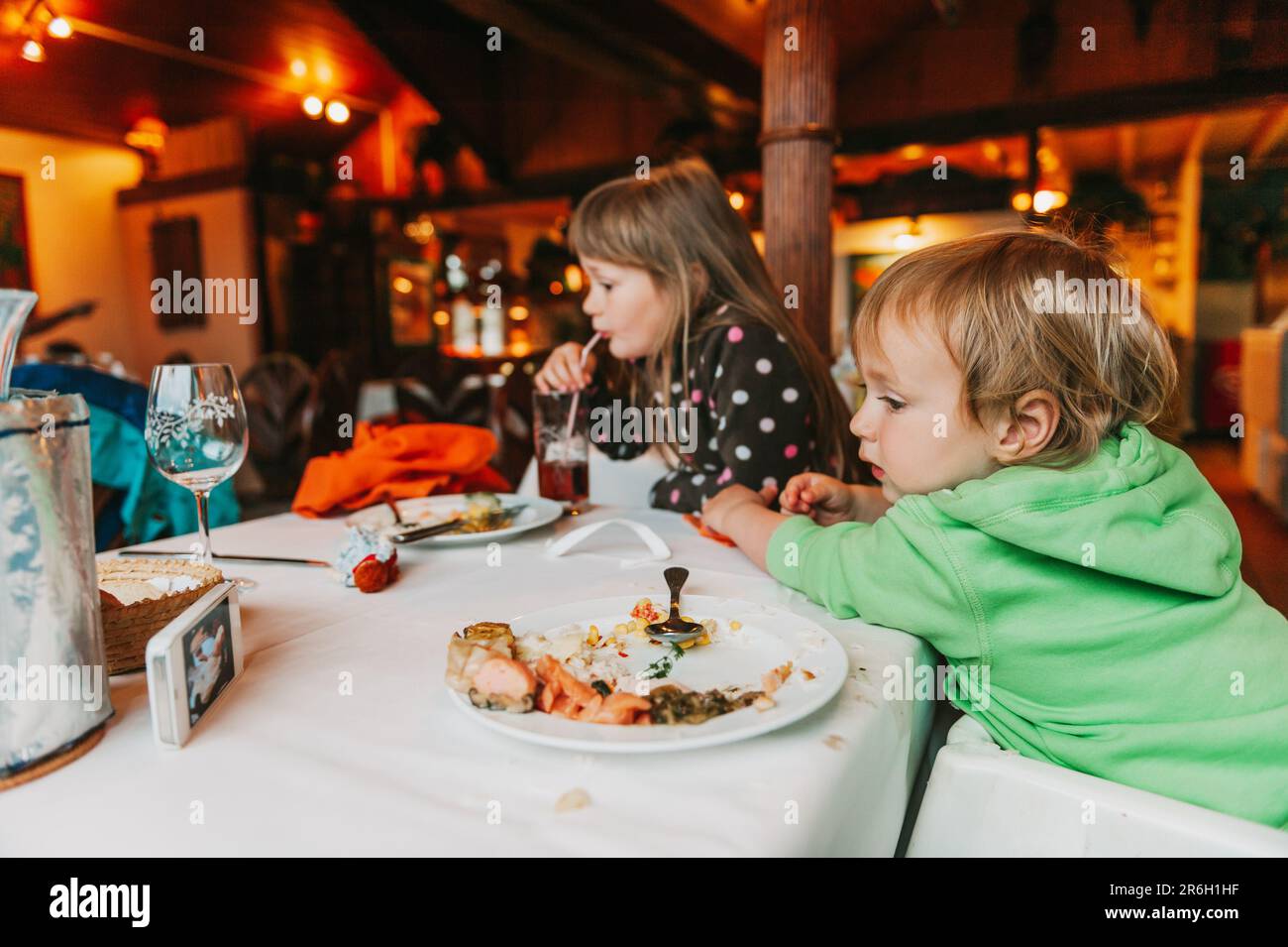 Due bambini disordinati mangiano il pranzo al ristorante, i bambini mangiano il cibo con le mani Foto Stock