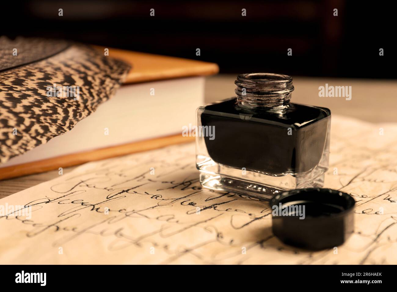 Open inkwell, piuma, libro e pergamena vintage con testo su tavola, primo piano Foto Stock