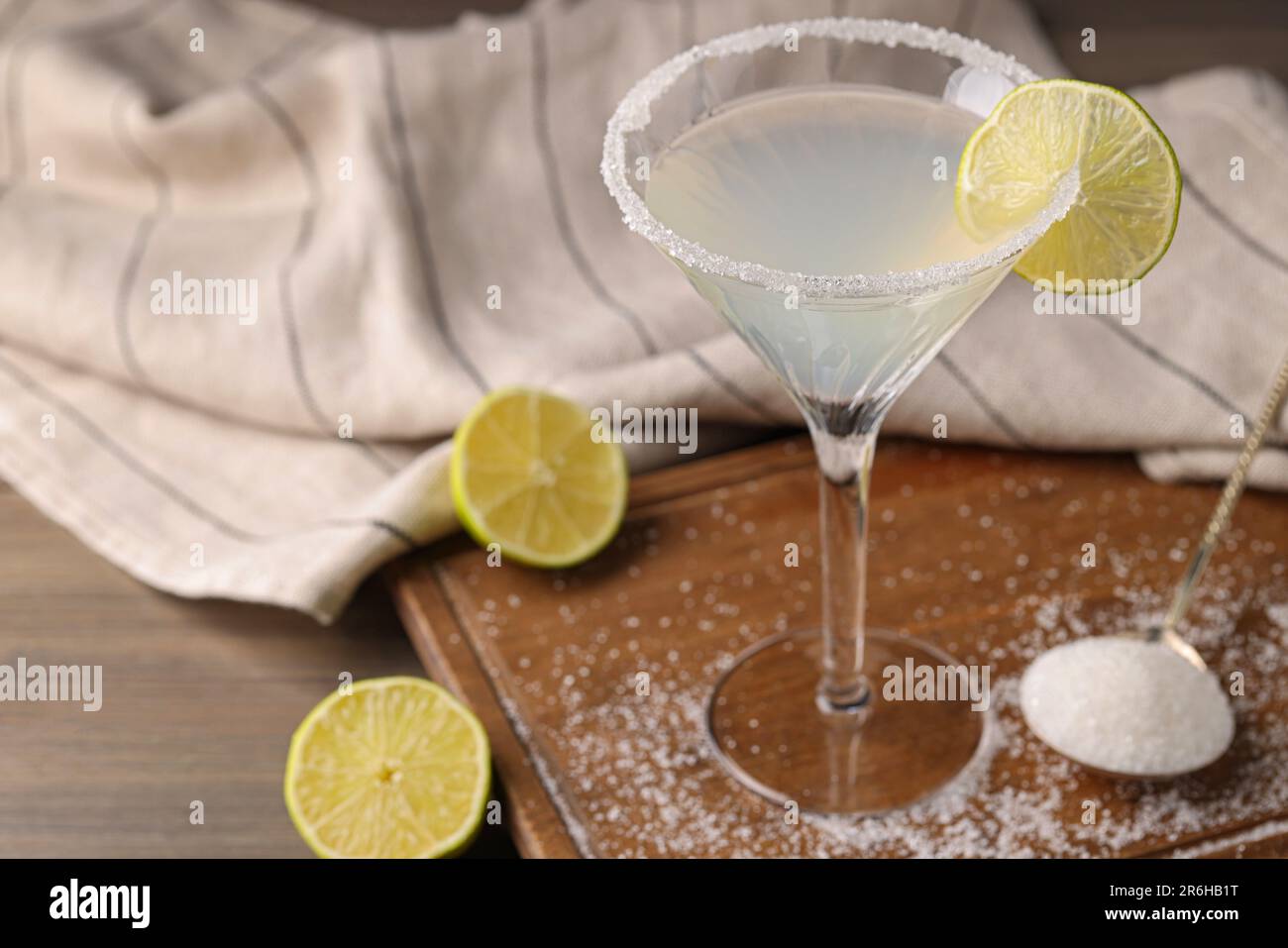 Martini bicchiere di cocktail rinfrescante con lime e zucchero su tavola di legno, primo piano Foto Stock