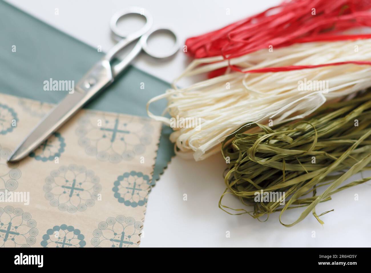 confezionamento artigianale. carta decorativa da imballaggio, forbici e matasse di corda naturale in rosso, bianco e verde su sfondo bianco Foto Stock