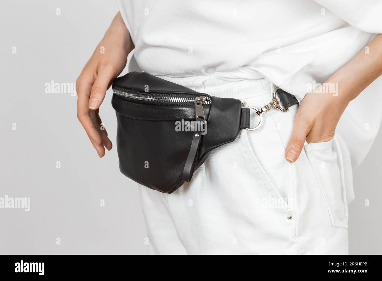 Borsa in vita in pelle nera per donna con jeans e camicia bianchi. Accessori in pelle fatti a mano Foto Stock