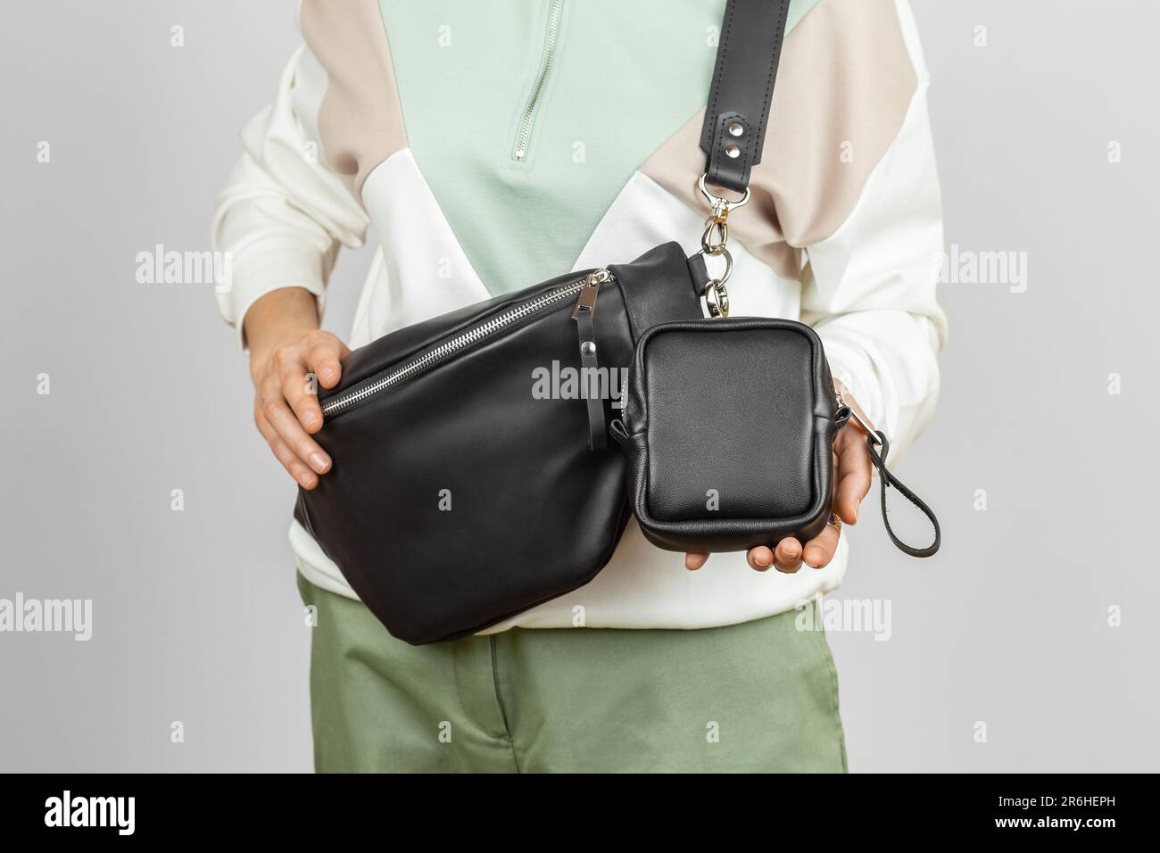 Piccola custodia in pelle attaccata alla tracolla Fanny Pack in vera pelle nera. Nessun modello Face Female su sfondo grigio, Studio Shot Foto Stock