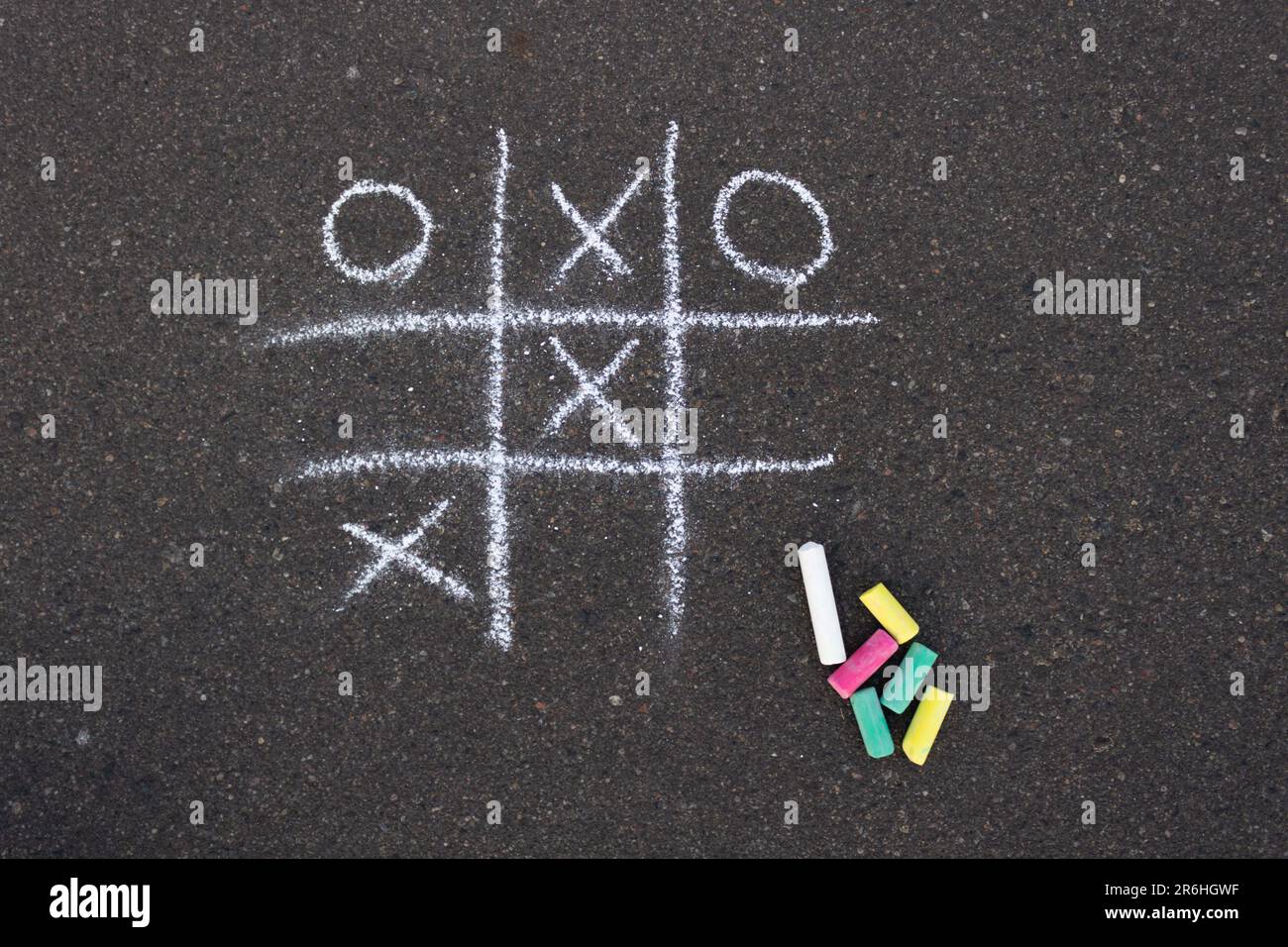 Disegno sul marciapiede disegnato con gesso bianco. Gioco TIC-tac-TOE. Accanto alla foto ci sono pezzi di gesso colorato. Foto Stock