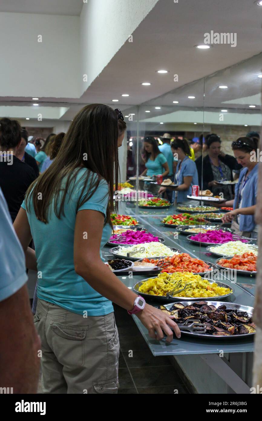 Una giovane donna sceglie il suo pasto da una selezione di cibi freschi esposti a un buffet in un ristorante israeliano. Foto Stock