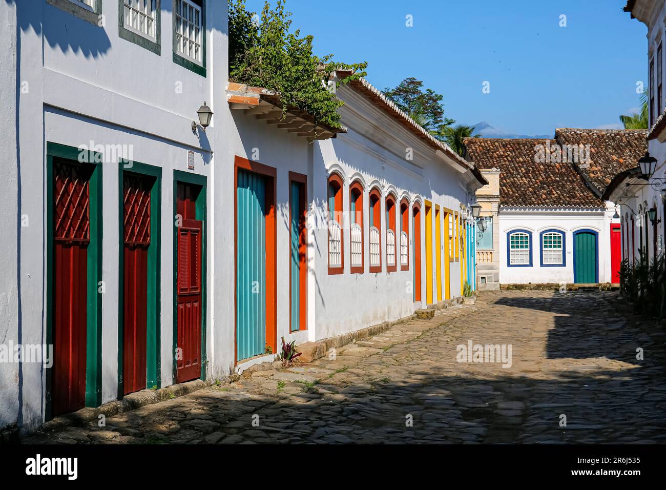 Tipica strada acciottolata con colorati edifici coloniali nel tardo pomeriggio sole nella città storica di Paraty, Brasile Foto Stock