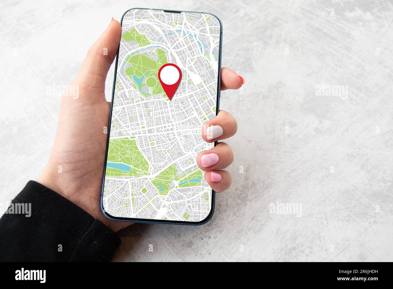 Ragazza che tiene in mano uno smartphone con l'immagine delle mappe on line. Spazio di copia per il fondo in marmo Foto Stock