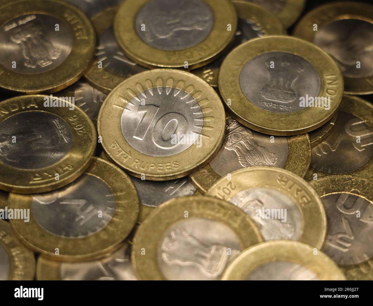 una collezione mista di rare monete d'epoca bimetalliche indiane da 10 (dieci) rupie, oro e argento in una pila Foto Stock