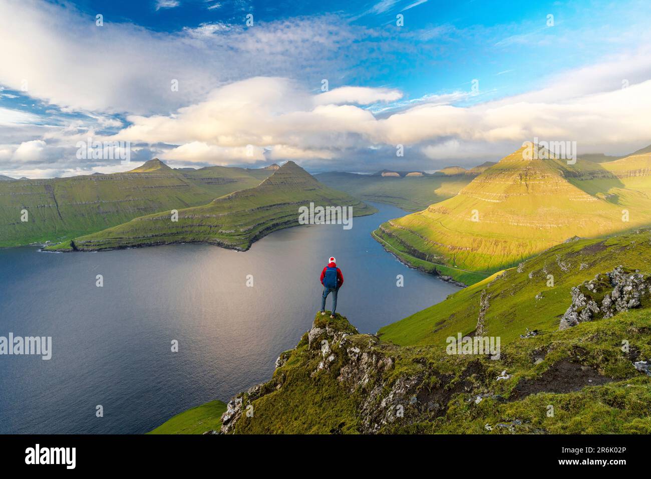 Escursionista con zaino godendo la vista in piedi sulle rocce che si affaccia Fjord Funningur, Isola di Eysturoy, Isole Faroe, Danimarca, Europa Foto Stock